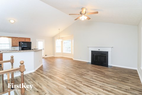 A spacious living room with wood flooring and a fireplace.
