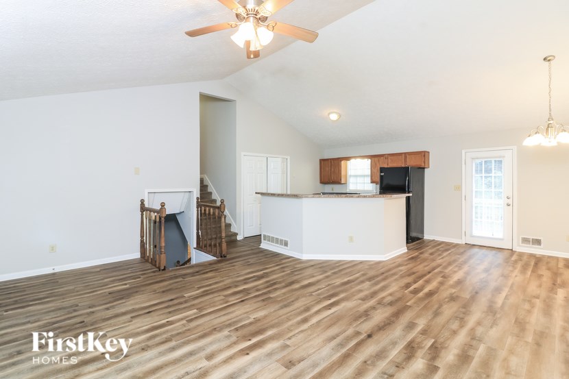 A spacious living room with wooden floors and a ceiling fan.