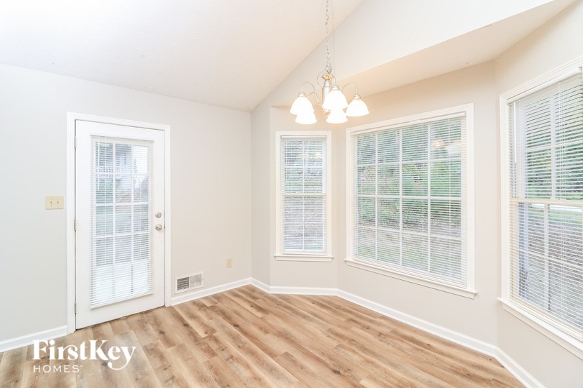 A room with wooden floors and three windows.
