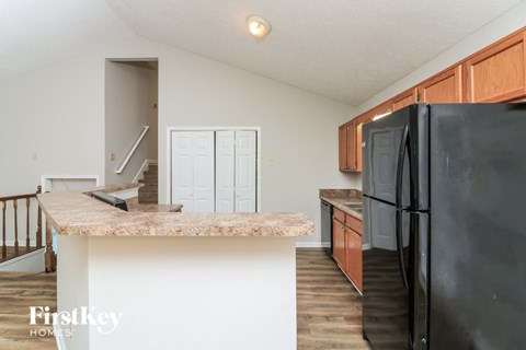 A kitchen with a black fridge and a counter top with a sink.