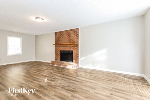 a living room with a brick fireplace and wooden floors