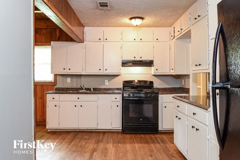 A kitchen with white cabinets and a black refrigerator.