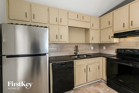 a kitchen with white cabinets and black appliances and a stainless steel refrigerator