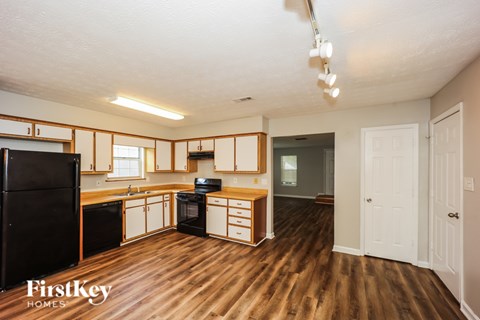 A kitchen with wooden floors and a black refrigerator.