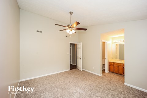 A bedroom with a carpeted floor and a ceiling fan.