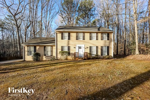 a yellow house in the woods with a white door