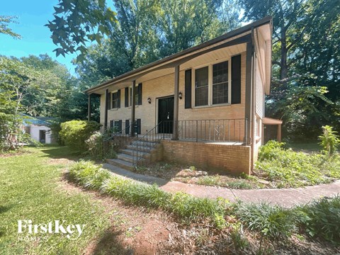 a small brown house with a yard and a sidewalk