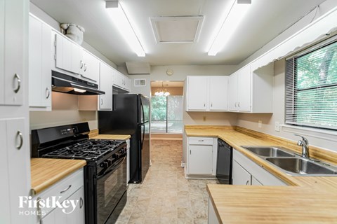 A kitchen with white cabinets and a black refrigerator.