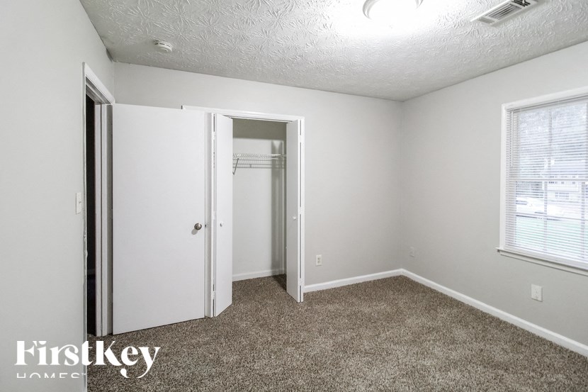 a bedroom with a closet and a window and a carpeted floor