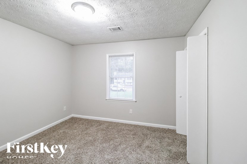 a bedroom with white walls and carpet and a window