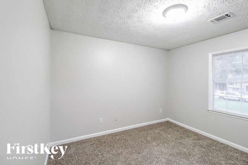 a bedroom with white walls and carpet and a window