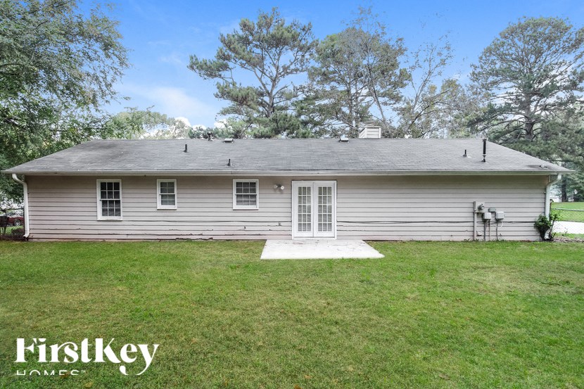 the front of a white house with a lawn and trees