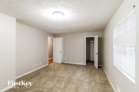 a spacious living room with carpet and a door to a hallway