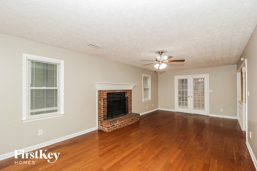 an empty living room with a fireplace and a ceiling fan