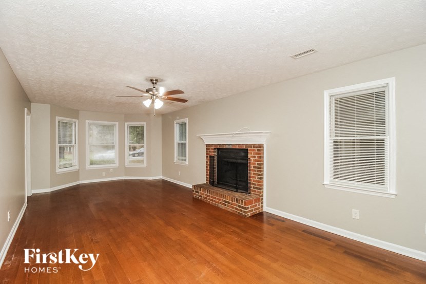 an empty living room with a fireplace and a ceiling fan