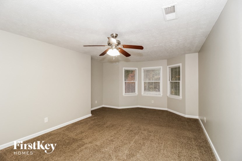 an empty living room with a ceiling fan and a carpet