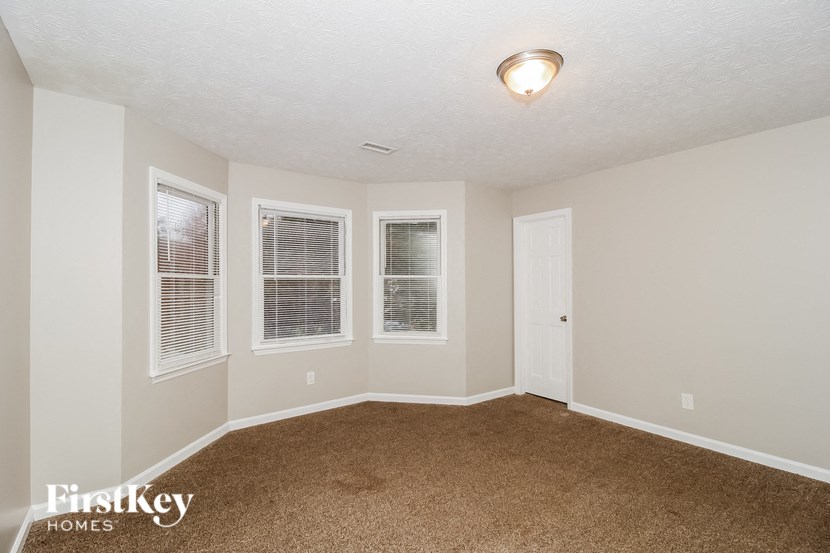 an empty living room with three windows and a door