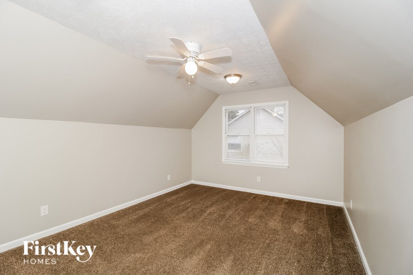 the bedroom has a carpeted floor and a ceiling fan