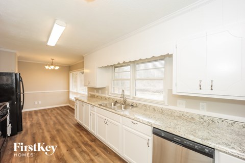 A kitchen with white cabinets and a granite countertop.