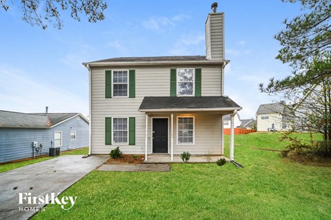 the front of a house with green shutters and a driveway