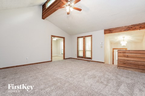 a living room with carpet and a ceiling fan
