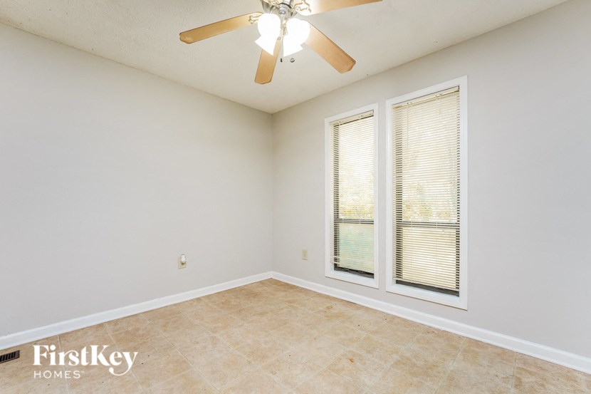 the living room of an empty house with a ceiling fan and two windows
