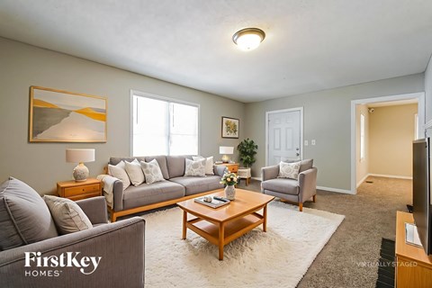 A living room with a grey couch, a wooden coffee table, and a painting on the wall.