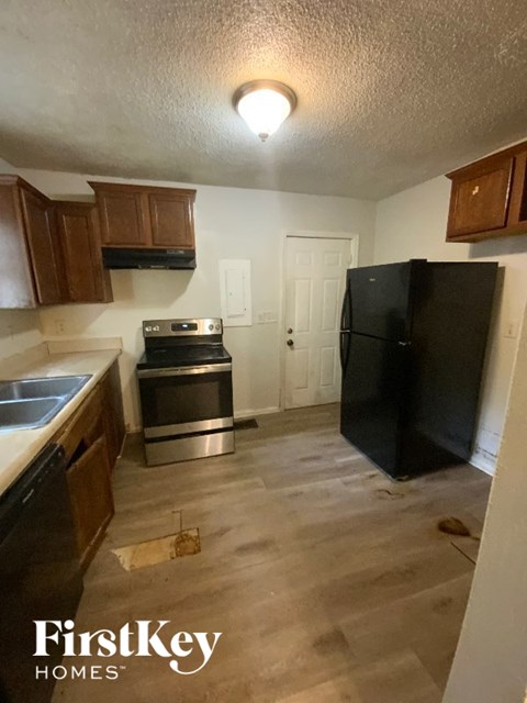 A kitchen with a black fridge and wooden cabinets.