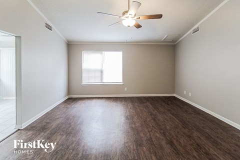 an empty living room with wood flooring and a ceiling fan