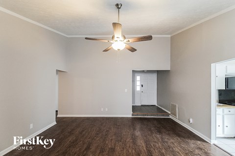 an empty living room with a ceiling fan