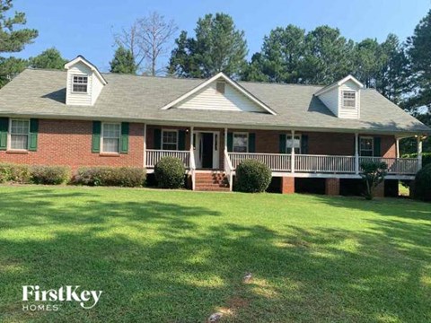 a brick house with a porch and a lawn