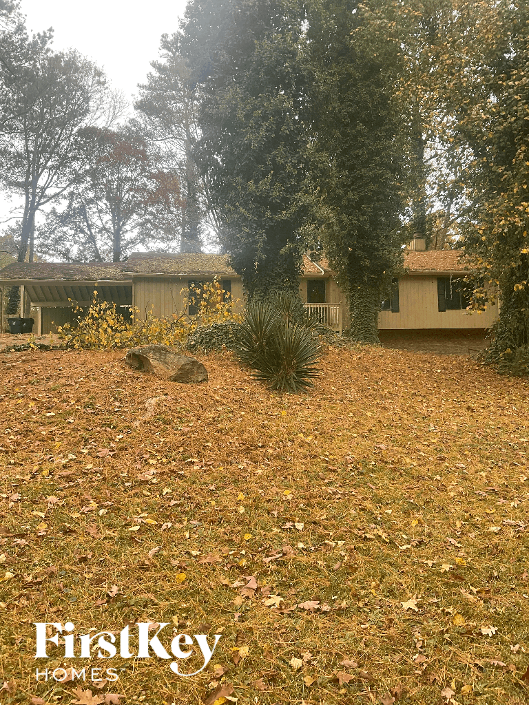 a house in the woods with a yard with dead grass