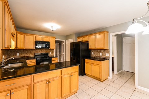 A kitchen with wooden cabinets and black countertops.