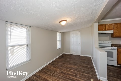 the living room and kitchen of an apartment with wood flooring and a white stove