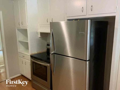 a stainless steel refrigerator in a kitchen with white cabinets
