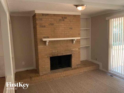 an empty living room with a brick fireplace and shelves