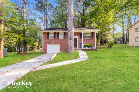 A house with a garage is surrounded by trees.