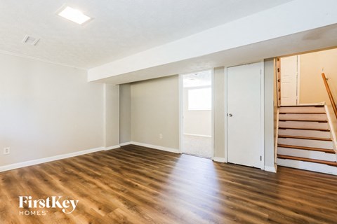 A room with wooden floors and a staircase on the right side.