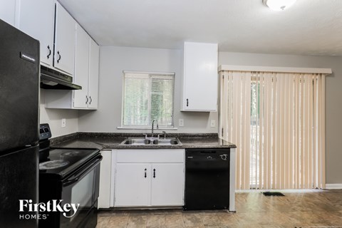 A kitchen with black appliances and white cabinets.