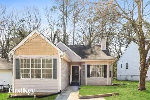 a small white house with a front porch and a tree