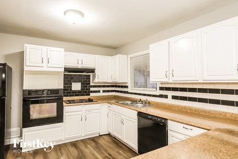 A kitchen with white cabinets and a black oven.