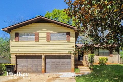 a small yellow house with two garage doors