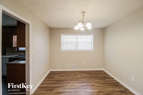 an empty dining room with wood flooring and a window