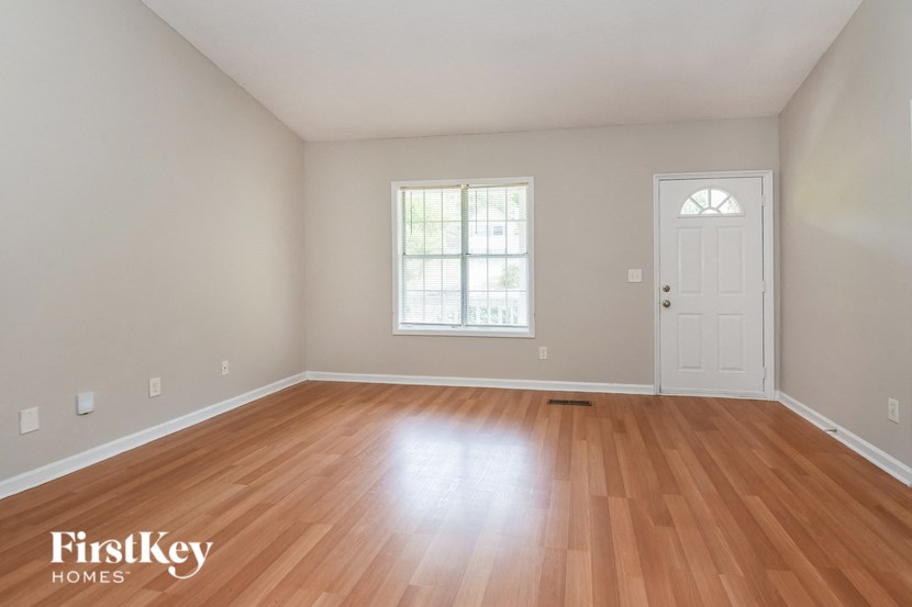 the spacious living room with hardwood flooring and a white door