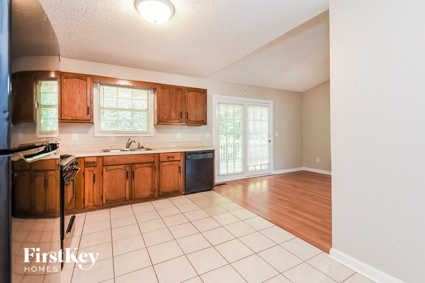 an empty kitchen with wooden cabinets and a white tiled floor