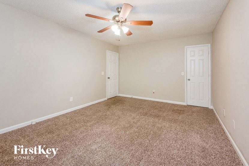 a spacious living room with carpet and a ceiling fan