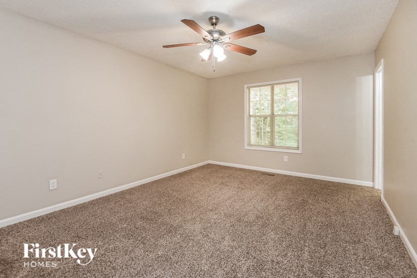 an empty living room with a ceiling fan and a window