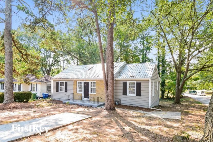 a small white house with a yard and trees