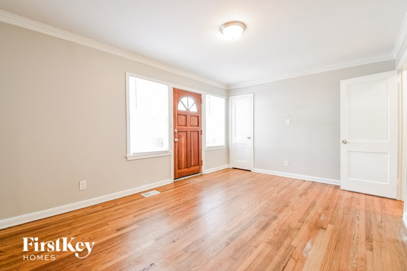the living room of a house with wood floors and a wooden door
