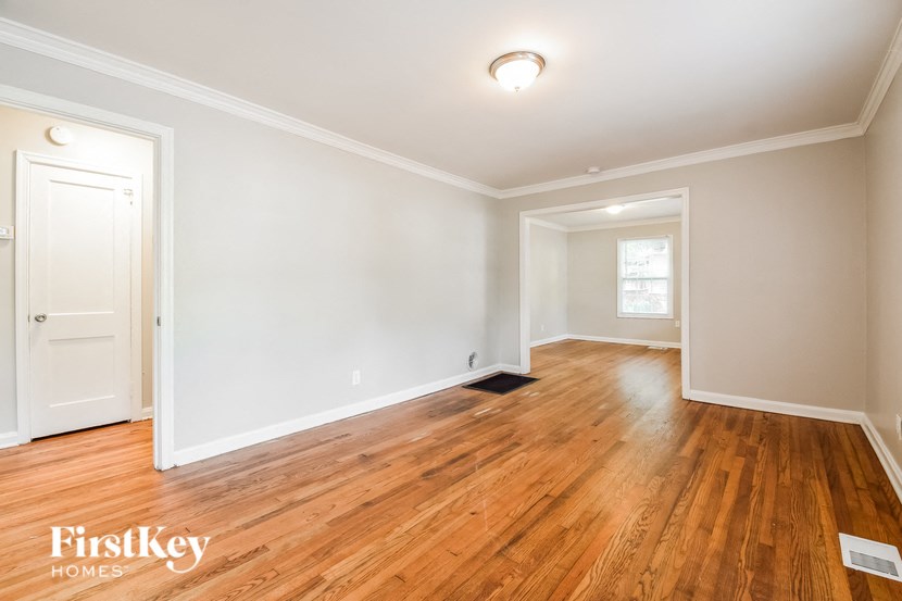 the living room and dining room with wood floors and white walls